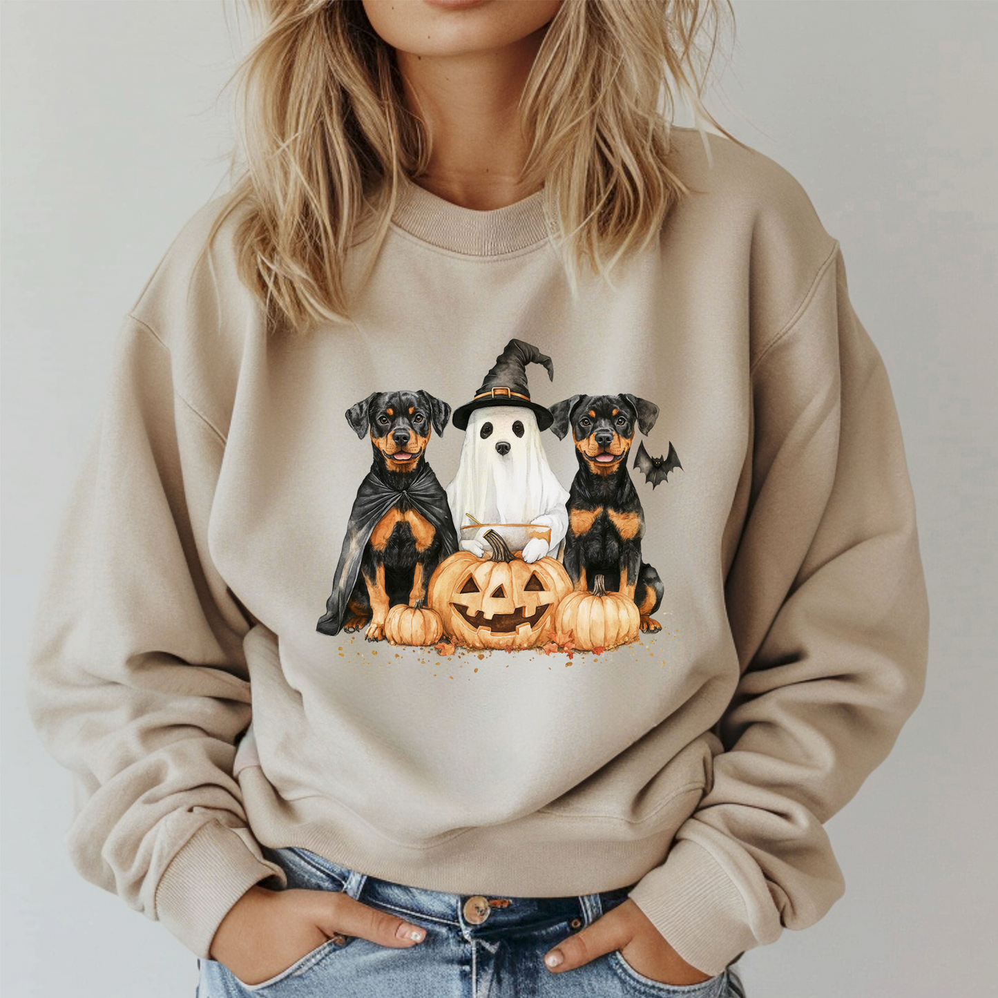 Person wearing a beige sweatshirt with Halloween-themed dog graphics.