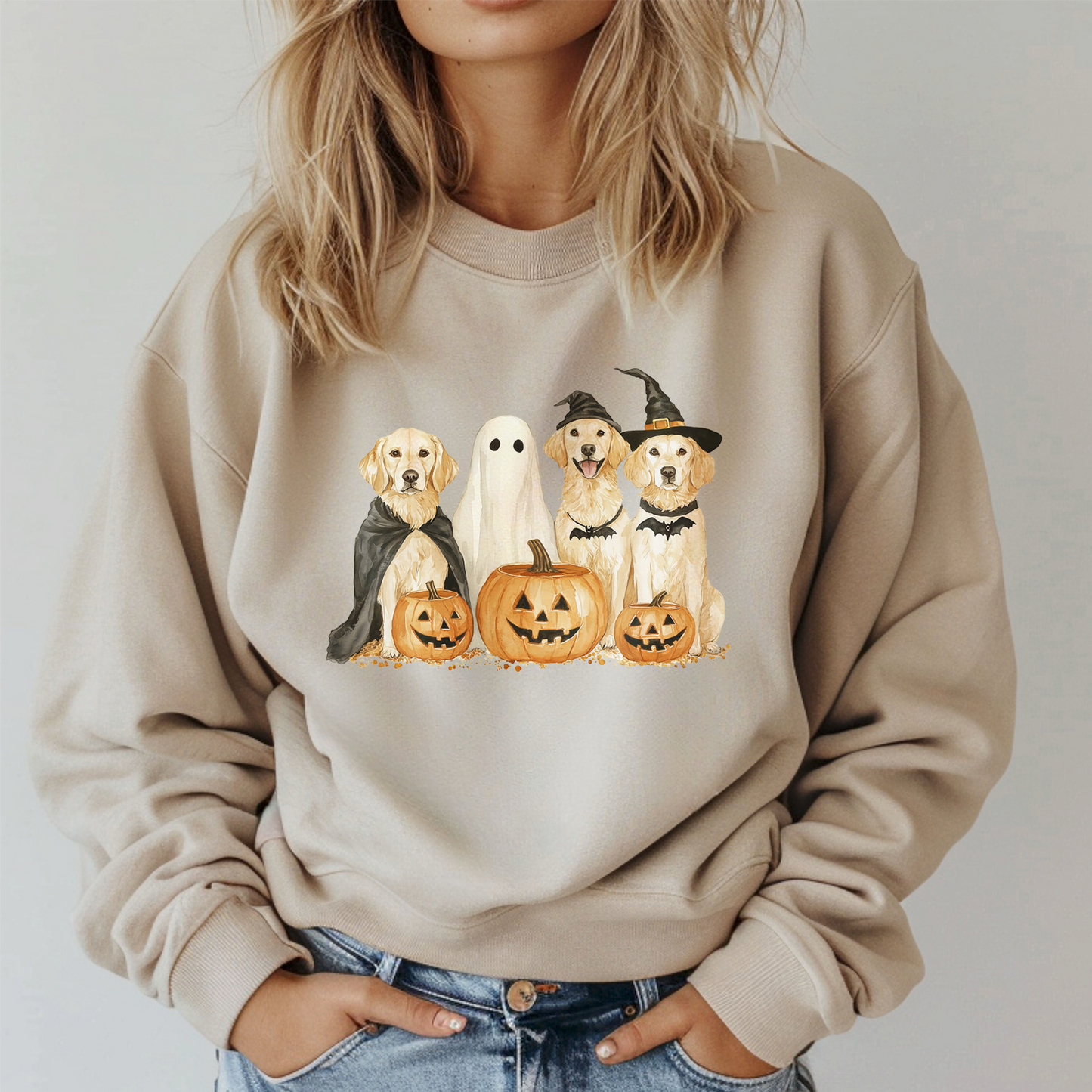 Beige sweatshirt with Halloween-themed design of dogs, ghosts, and pumpkins worn by a person.